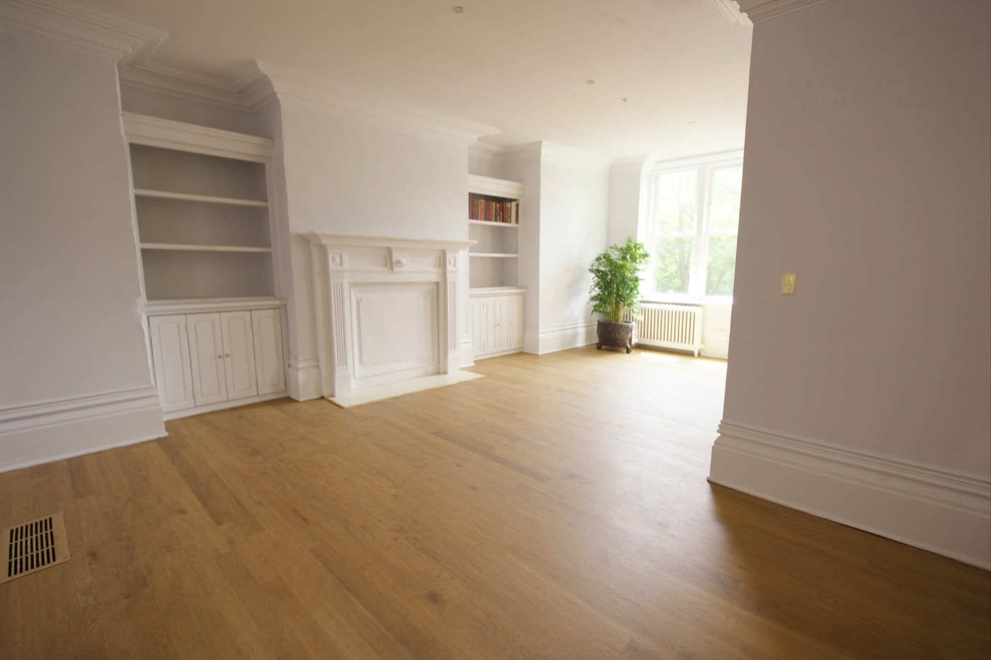 Renovated living room with refinished hardwood floors and white painted trim